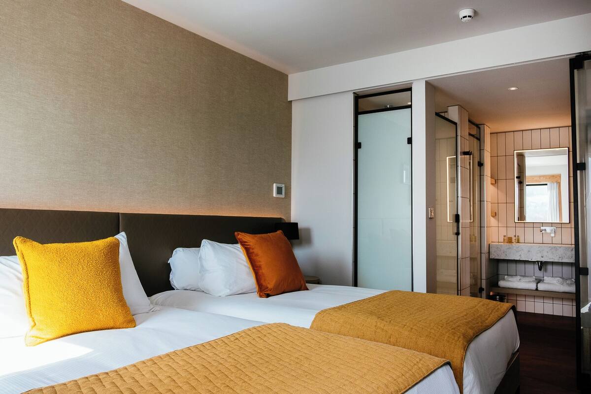 A hotel room with a bed, a bathroom, and a sliding door to another room.