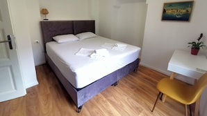 A neatly made bed with white linens, a small desk with a chair, and a potted plant. - Apartment Mama H (Dubrovnik)
