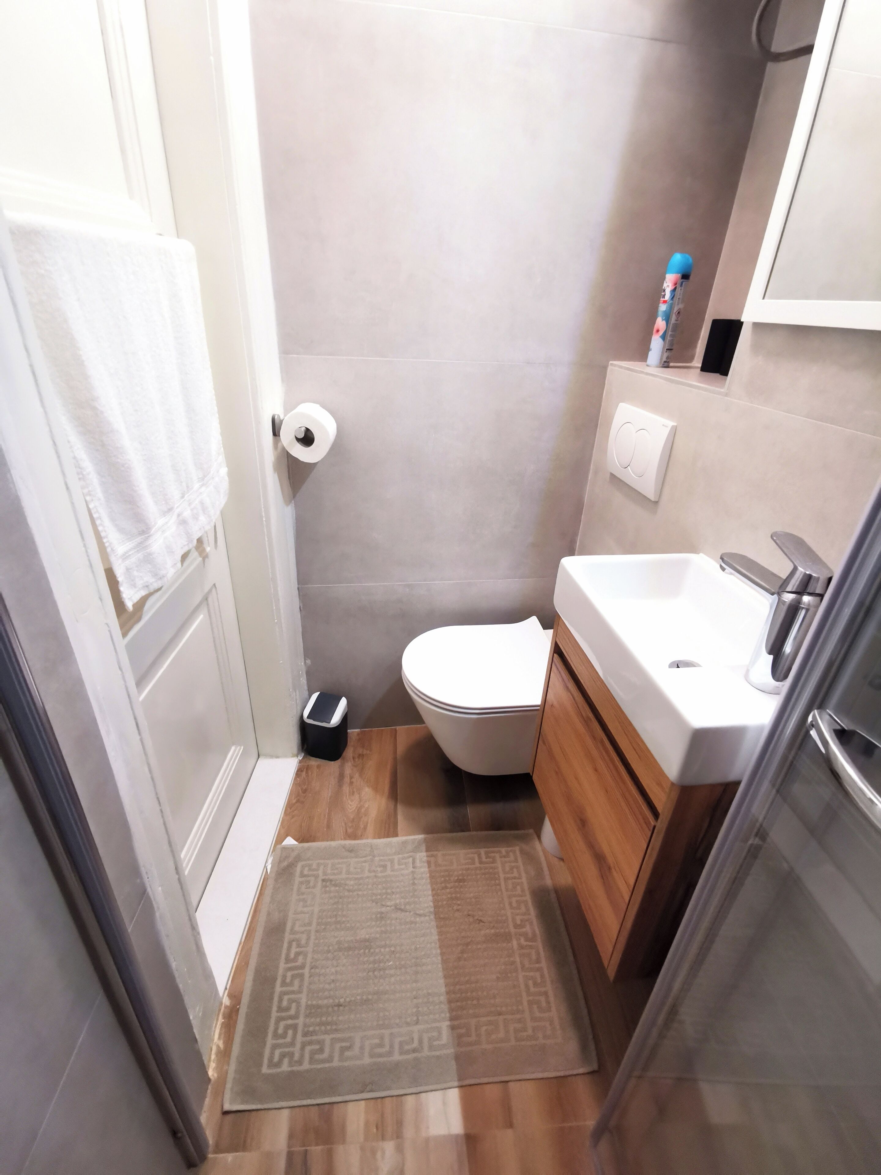 Ein kleines Badezimmer mit Toilette, Waschbecken und einem kleinen Mülleimer.