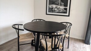 Ein Essbereich mit einem runden Tisch und vier Stühlen, einem schwarzen und weißen Foto im Rahmen an der Wand und Holzboden.