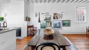 A dining area with a wooden table, chairs, and a rustic bowl centerpiece. - Oak Loft Downtown, Steps to King St Bars & Restaurants (Charleston)