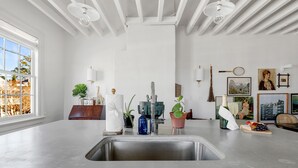 A modern kitchen with a large island, stainless steel sink, and various decorative items. - Oak Loft Downtown, Steps to King St Bars & Restaurants (Charleston)