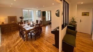 A spacious dining area with a wooden table and chairs, a kitchen area with wooden cabinets, and a staircase leading to another level.