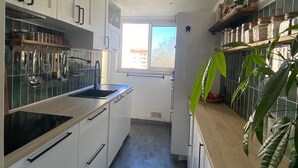 A modern kitchen with white cabinets, a black stove, and a window providing natural light.