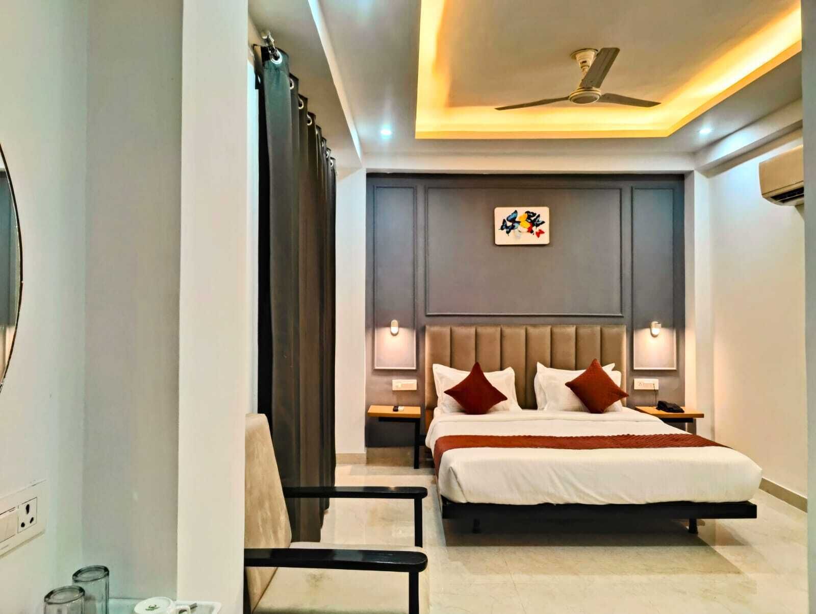 Een moderne hotelkamer met een groot bed, twee nachtkastjes, een plafondventilator en een kunstwerk aan de muur.