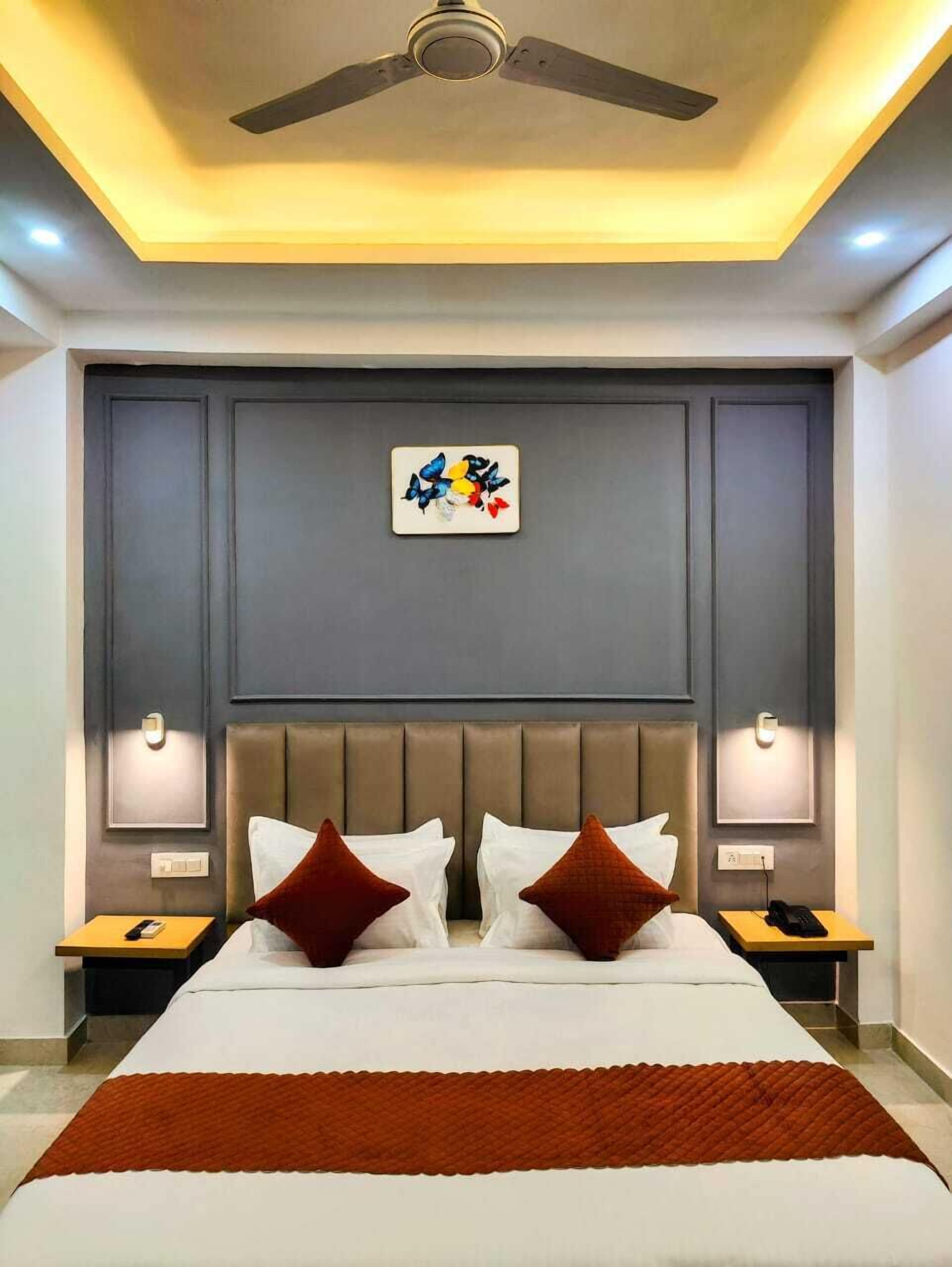 Une chambre d’hôtel moderne dotée d’un grand lit, d’un ventilateur de plafond, d’un éclairage encastré et d’un élément décoratif mural.