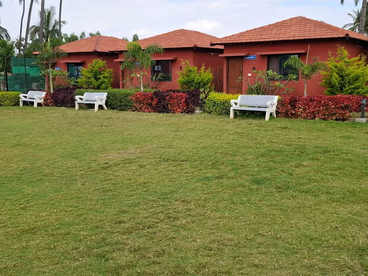 Um edifício com telhado vermelho e cadeiras de descanso brancas na frente.