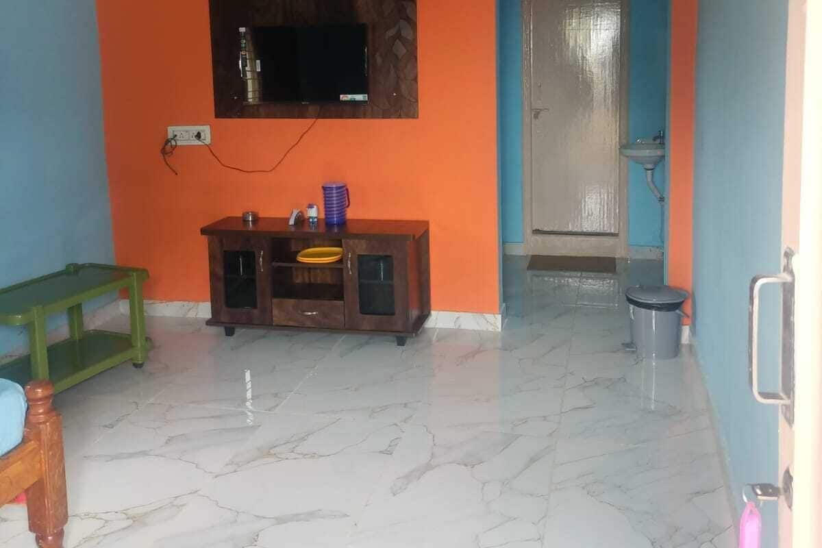 A room with a marble floor, a wooden cabinet, a television mounted on the wall, and a ceiling fan.