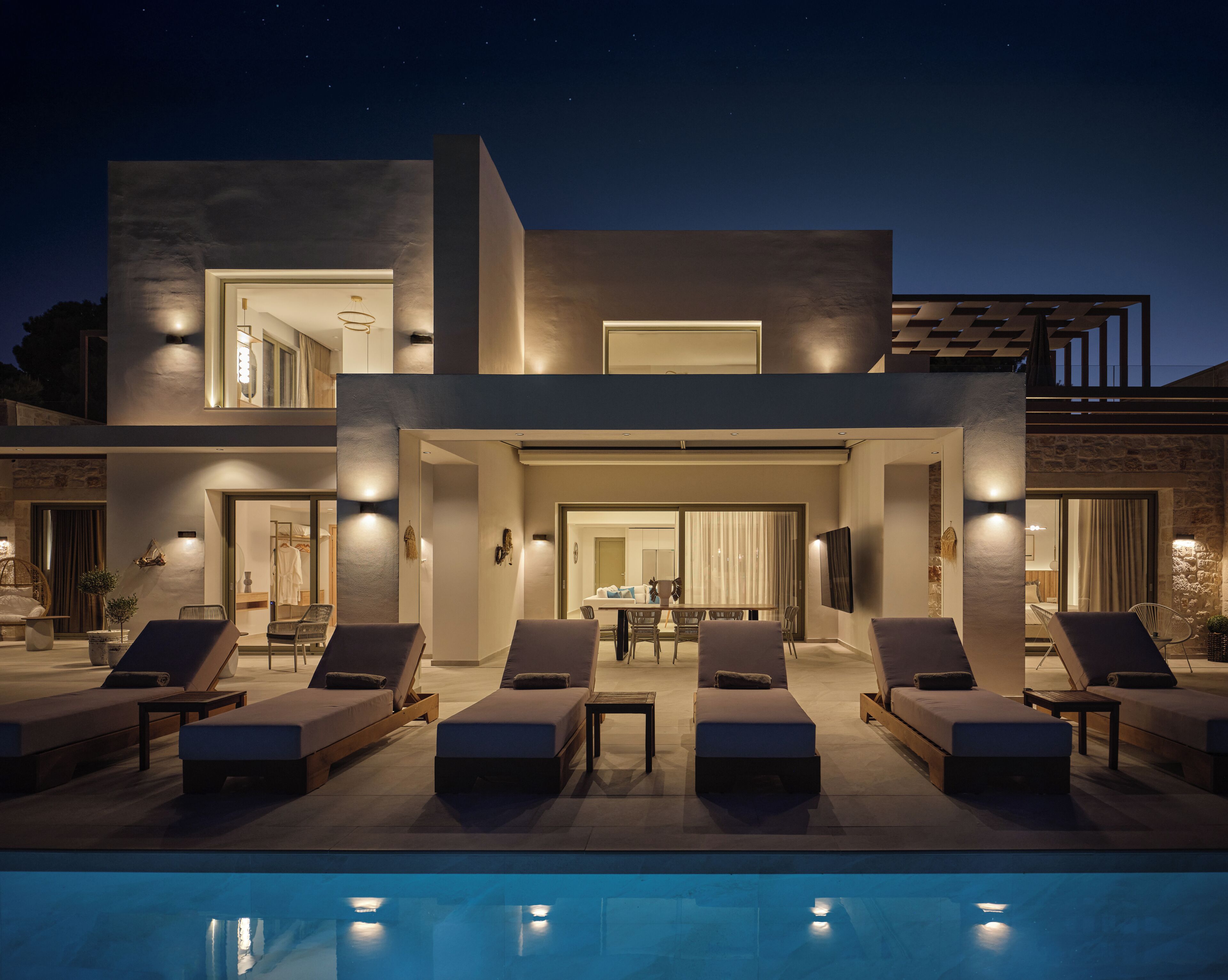 A modern two-story house with a pool, outdoor seating, and a dining area.