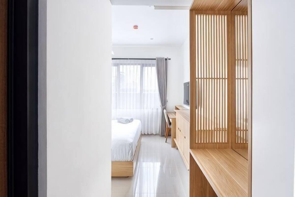 Habitación de hotel con cama, escritorio, televisor y puerta corredera.