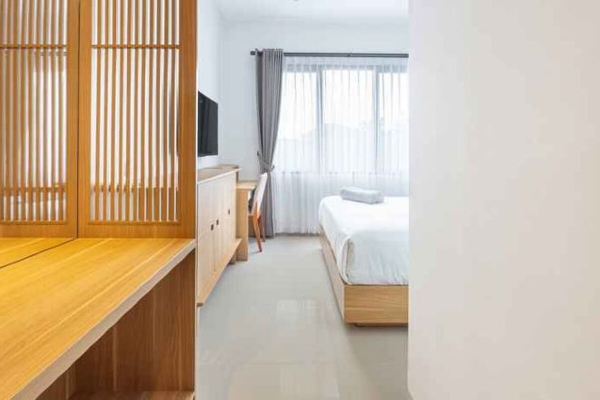 Una habitación de hotel con una cama, un escritorio, un televisor y un panel de madera.