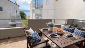 Una terraza con una mesa de madera dispuesta para dos personas, un frutero y un florero.