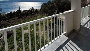 Ein Balkon mit Blick auf das Meer und die entfernten Hügel.