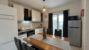 Eine moderne Küche mit weißen Schränken, einem Holztisch und einem Edelstahl-Kühlschrank.