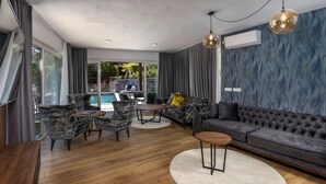 A modern living room with a pool view, wooden flooring, and a grey sofa. - NEW! Villa with 6 Bedrooms and Heated Pool (Moscenicka Draga)