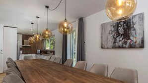 A modern dining area with a wooden table, multiple chairs, and pendant lighting. - NEW! Villa with 6 Bedrooms and Heated Pool (Moscenicka Draga)