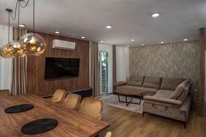 Una sala de estar moderna con una mesa de comedor de madera, sofás de cuero y un televisor de pantalla plana montado en la pared.