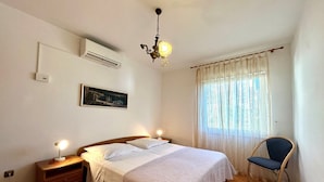 Une chambre à coucher avec un lit, des lampes de chevet, une chaise, un tableau au mur et un lustre.