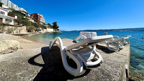 Une vue sur la plage, avec des chaises longues et une mer d’un bleu limpide.