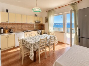 A kitchen with a dining area, a view of the sea, and a balcony. - Azure Apartments By The Sea with 3 Bedrooms (Omis)