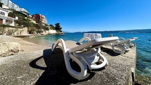 A beachside view with lounge chairs and a clear blue sea. - Azure Apartments By The Sea with 3 Bedrooms (Omis)