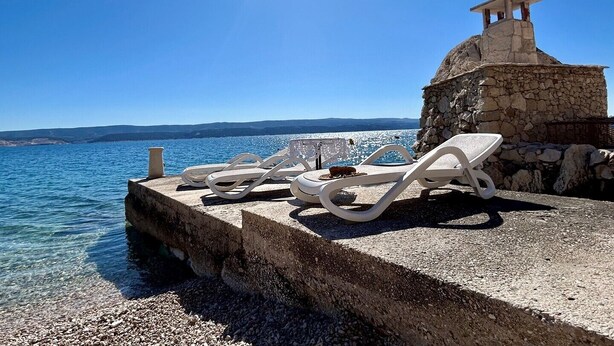 A stone structure with a small pavilion, white lounge chairs, and a clear view of the sea. - Azure Apartments By The Sea with 3 Bedrooms (Omis)