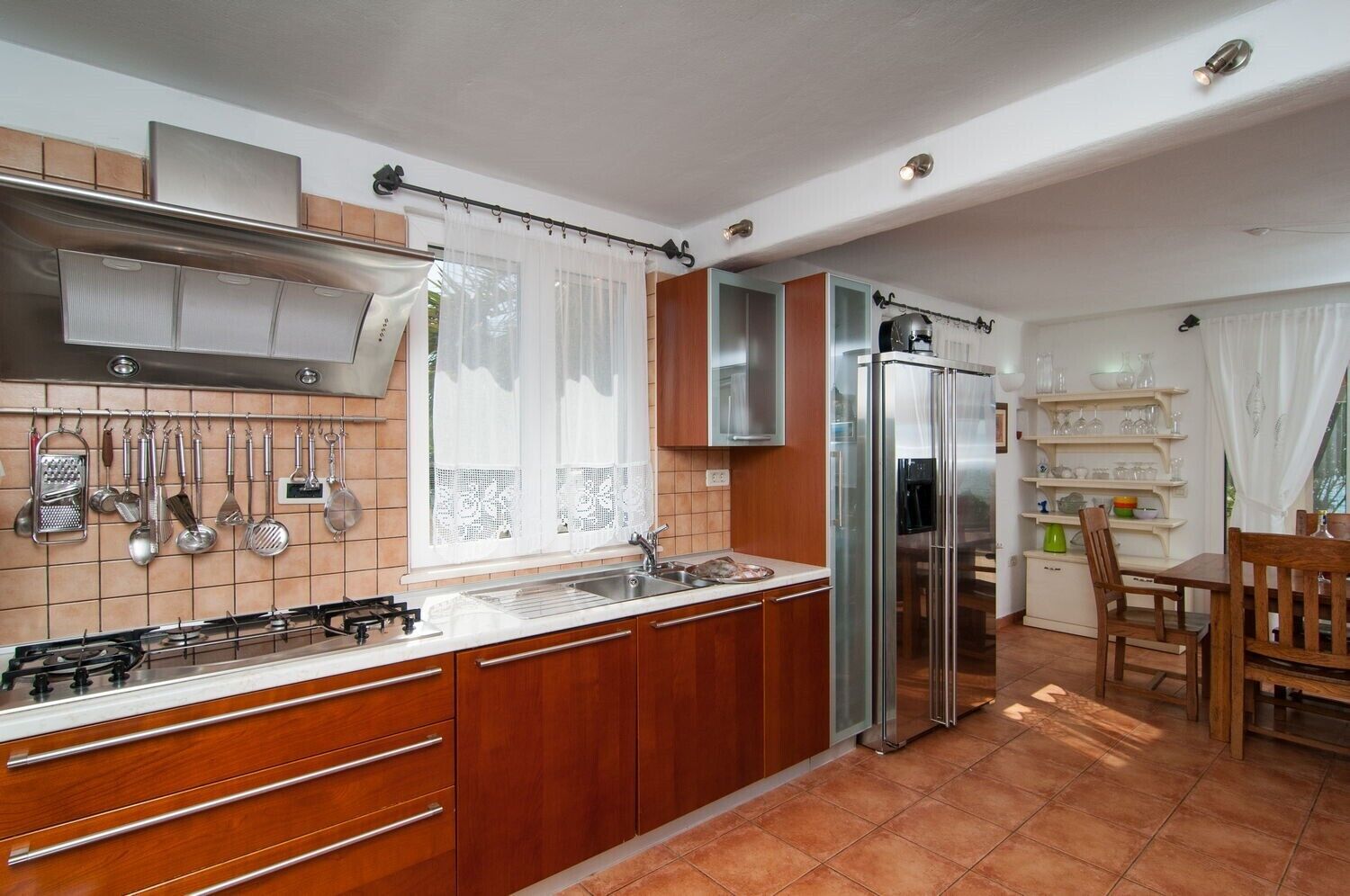 Una cucina con mobili in legno, un frigorifero in acciaio inox e un piano cottura a gas.