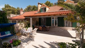 A house with a tiled roof, a covered patio with outdoor furniture, and a stone wall. - NEW! Exclusive Beachfront Villa with Pool for 8 at Island Brač (Mirca)