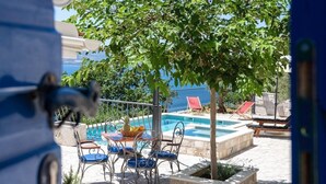 A pool area with a table and chairs, a tree, and a view of the sea. - NEW! Lovely Villa With Heated Pool and Sea View (Omis - Split Region)