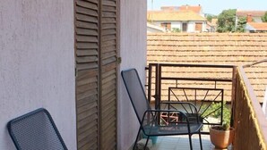 Un balcon avec deux chaises en métal et une plante en pot.
