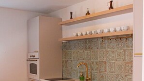 Une cuisine compacte avec des meubles blancs, un plan de travail en bois et un revêtement mural en carreaux.
