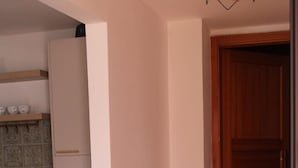 Une cuisine avec des meubles blancs, un plan de travail et un revêtement mural en carreaux.