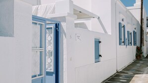 Una calle estrecha con edificios blancos y puertas azules, evocando un ambiente mediterráneo.