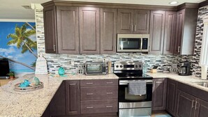 A modern kitchen with dark wood cabinets, a stainless steel microwave, a toaster, and a gas stove. - HUGE GameRoom | Steps 2 Beach | Golf Simulator | Movie Theater (Daytona Beach)