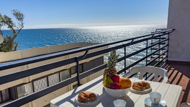 Ein Balkon mit Frühstückstisch, mit Blick auf das klare, blaue Meer.