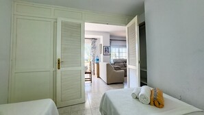 Ein Hotelzimmer mit zwei Betten, einer Tür zu einem Wohnbereich und Blick ins Freie.