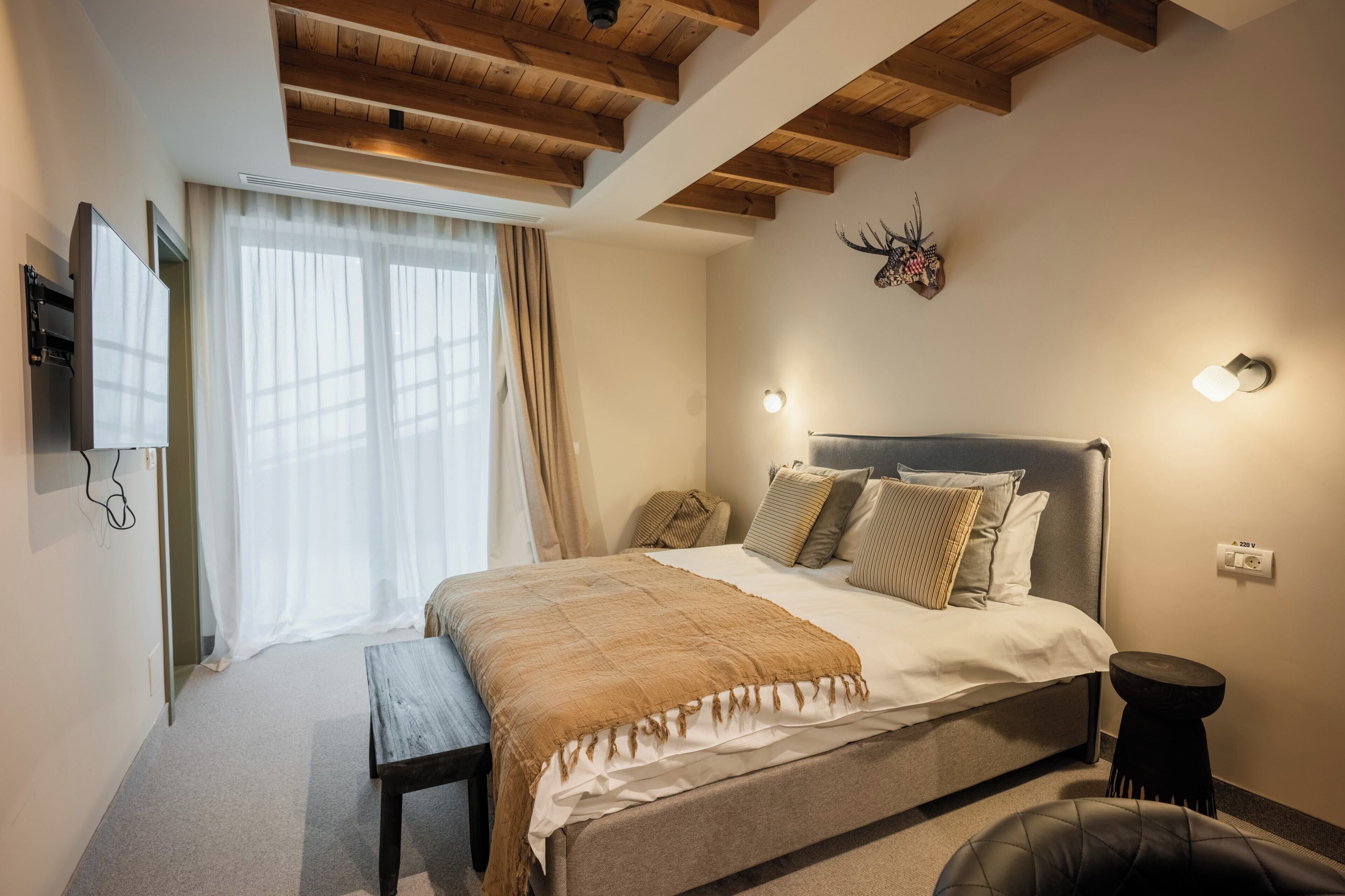 Un dormitorio con cama, mesita de noche y televisor instalado en la pared.
