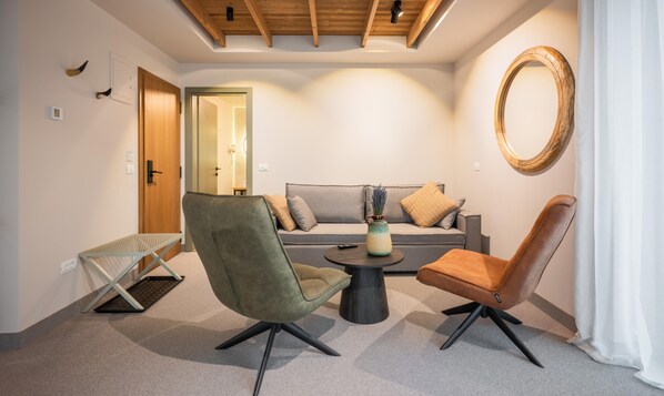 A modern living room with a sofa, two armchairs, a coffee table, and a mirror on the wall. - The Pines Bucegi Lodge  (Bran)