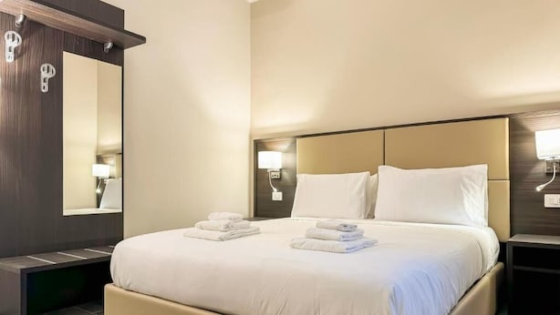 Et hotelværelse med en stor seng, en kommode i mørkt træ og to sengeborde med lamper.