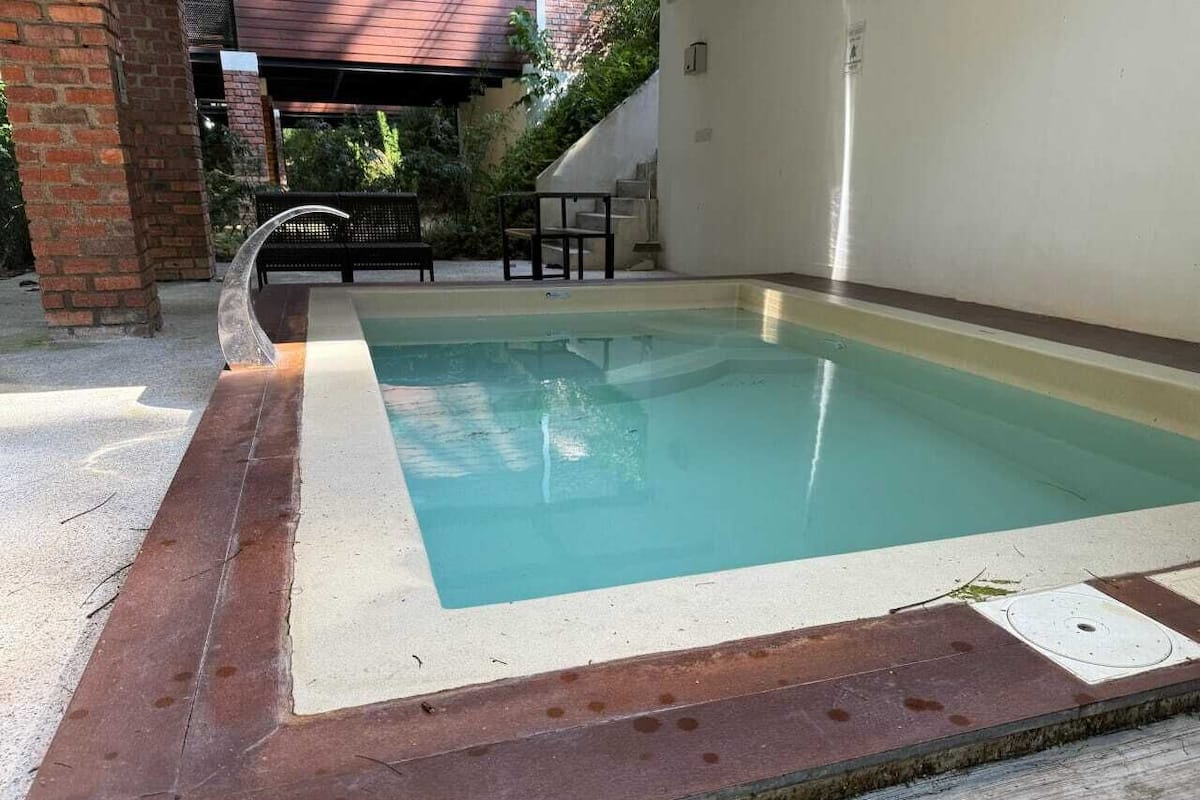 Piscina ao ar livre com borda de concreto e corrimão de metal.