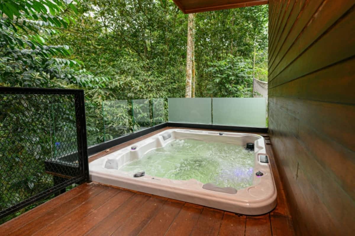 Uma banheira de hidromassagem em deck de madeira, com vista para vegetação densa.