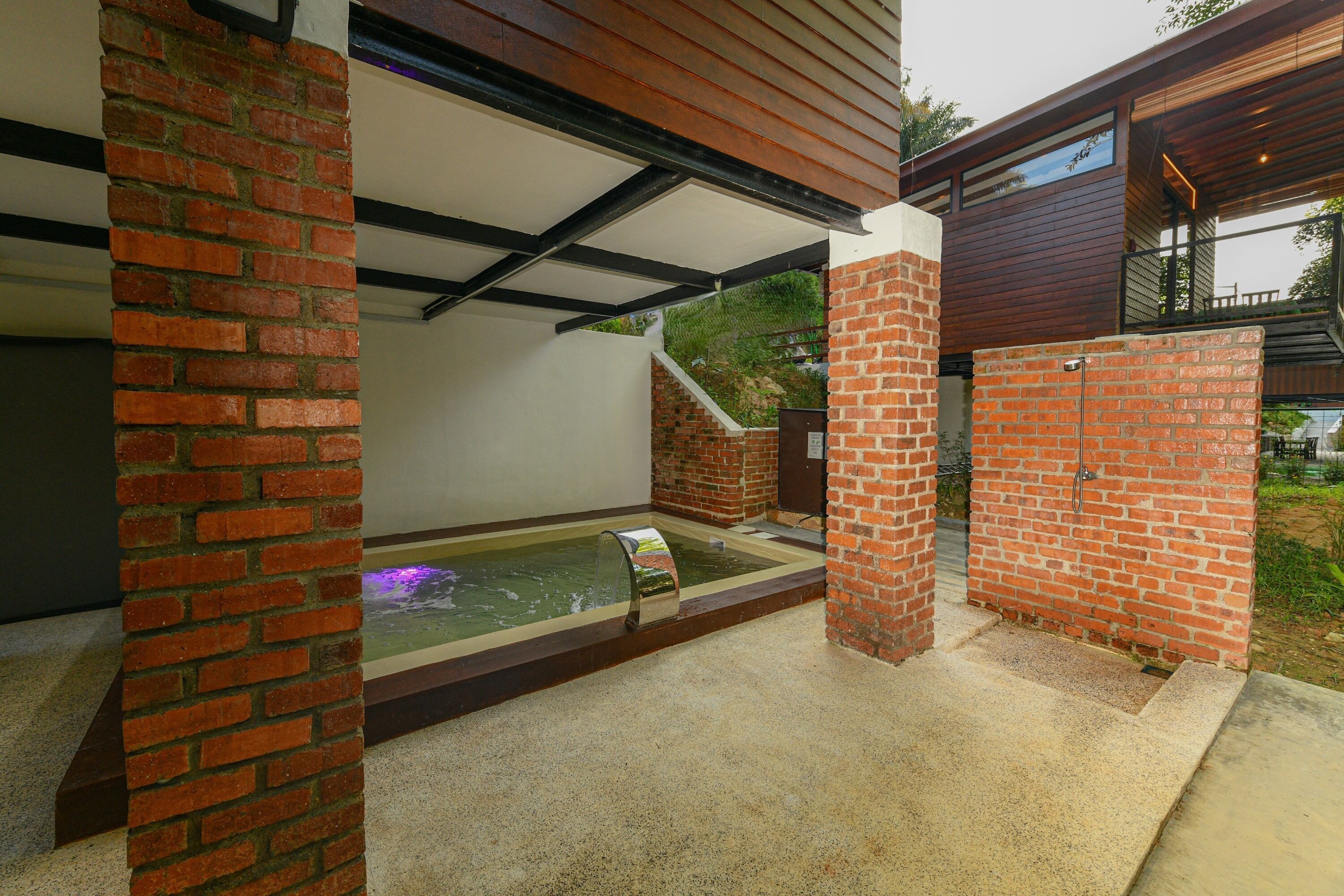 A spa area with a hot tub, brick walls, and a wooden ceiling.