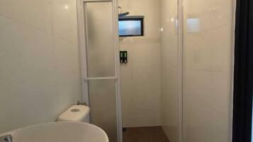A bathroom with a large sink, toilet, and glass-enclosed shower.