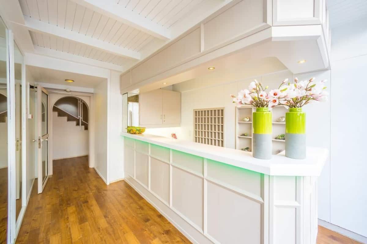 A modern kitchen with white cabinetry, a wooden floor, and a green-lit countertop.