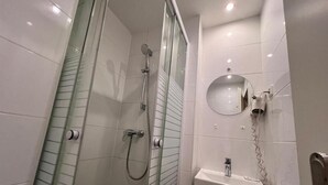 Ein modernes Badezimmer mit einer Duschkabine, einem Waschbecken mit Spiegel und einem Handtuchhalter.