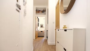 Ein schmaler Flur mit Holzboden, weißen Wänden und einem weißen Kleiderschrank mit Spiegel.
