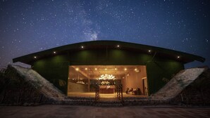 A building with a large open entrance, a starry night sky, and a chandelier inside. - Vanya Forest Resort (Kaladhungi)