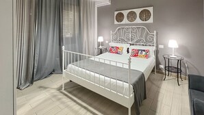 A bedroom with a white metal bed frame, grey curtains, a ceiling fan, and a wall-mounted lamp.
