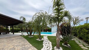 A landscaped outdoor area with a stone pathway, a pool, and various plants.