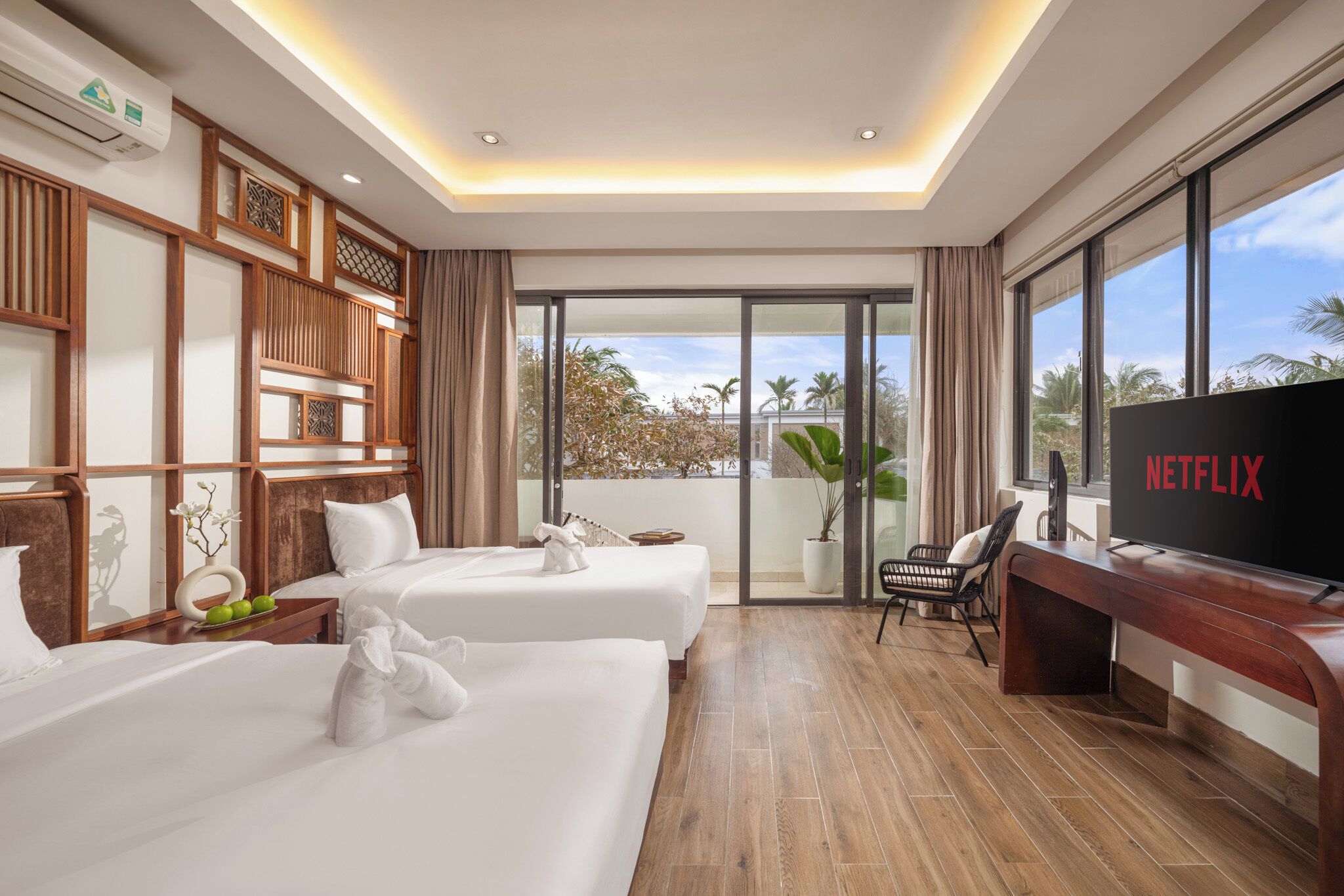 A hotel room with two beds, a TV, and a balcony with a view.